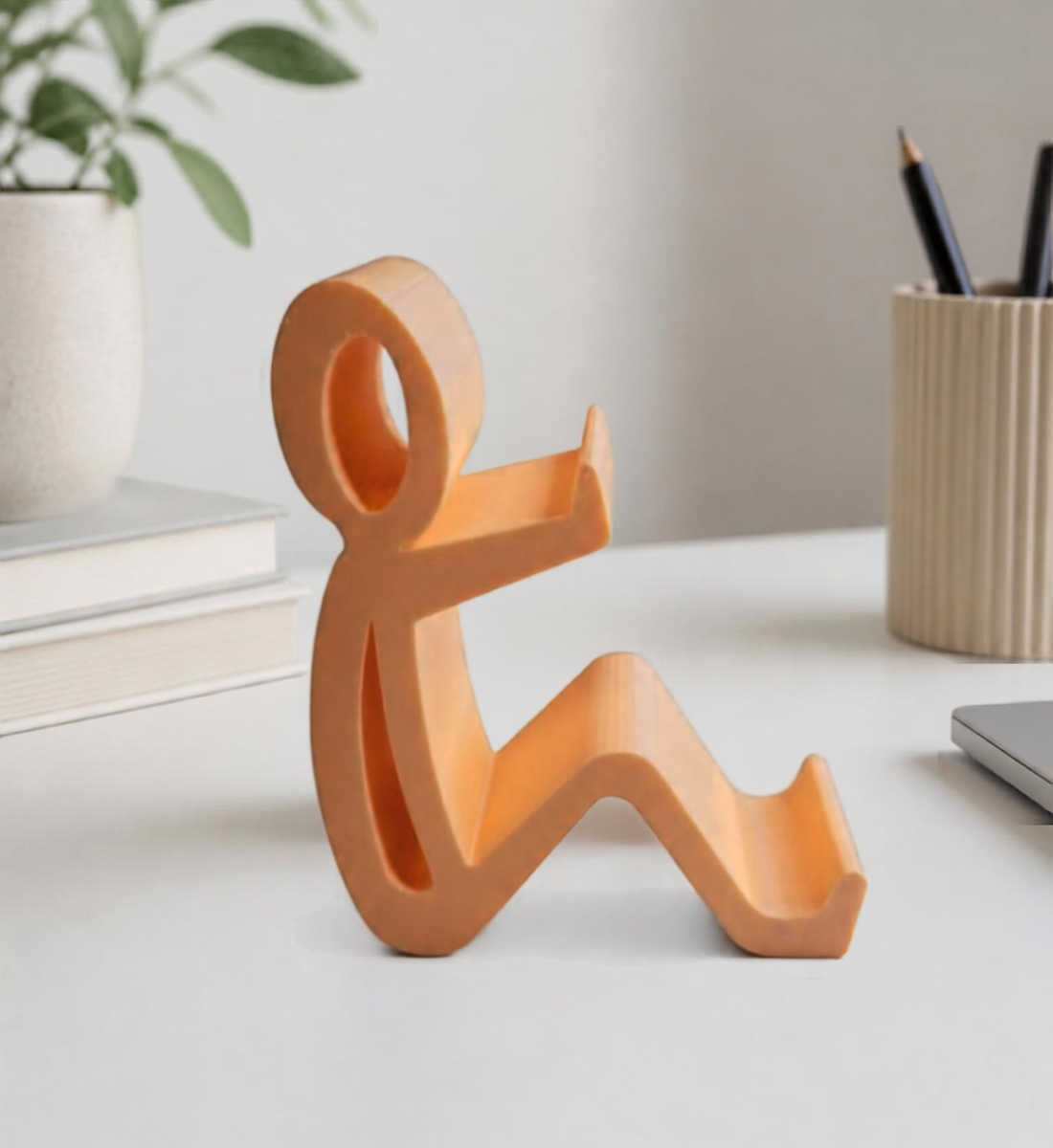Perzikkleurige telefoonhouder in de vorm van een zittend mannetje
